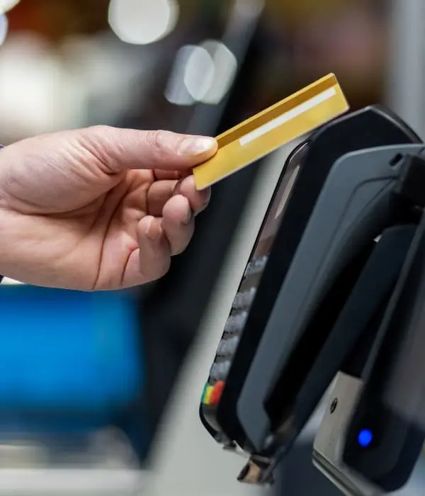 Cliente realizando un pago sin contacto con una tarjeta de crédito en unterminal POS, ilustrando la optimización del procesamiento de tarjetas