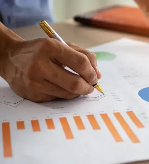 Person reviewing financial charts and graphs with a calculator, focused onoptimizing card brand agreements