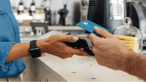 Cardholder making a contactless payment via POS terminal, illustratingdebit and credit card processing optimization