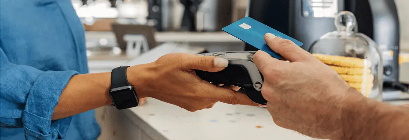 Cliente realizando un pago sin contacto en un terminal POS, ilustrando laoptimización del procesamiento de tarjetas de débito y crédito