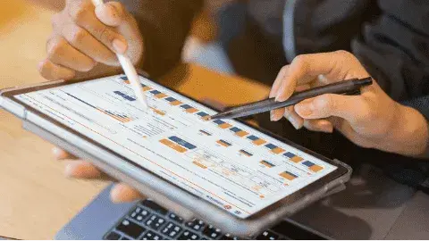 Two people reviewing cost analysis on a tablet with charts, representinghidden fees in card payment processing.