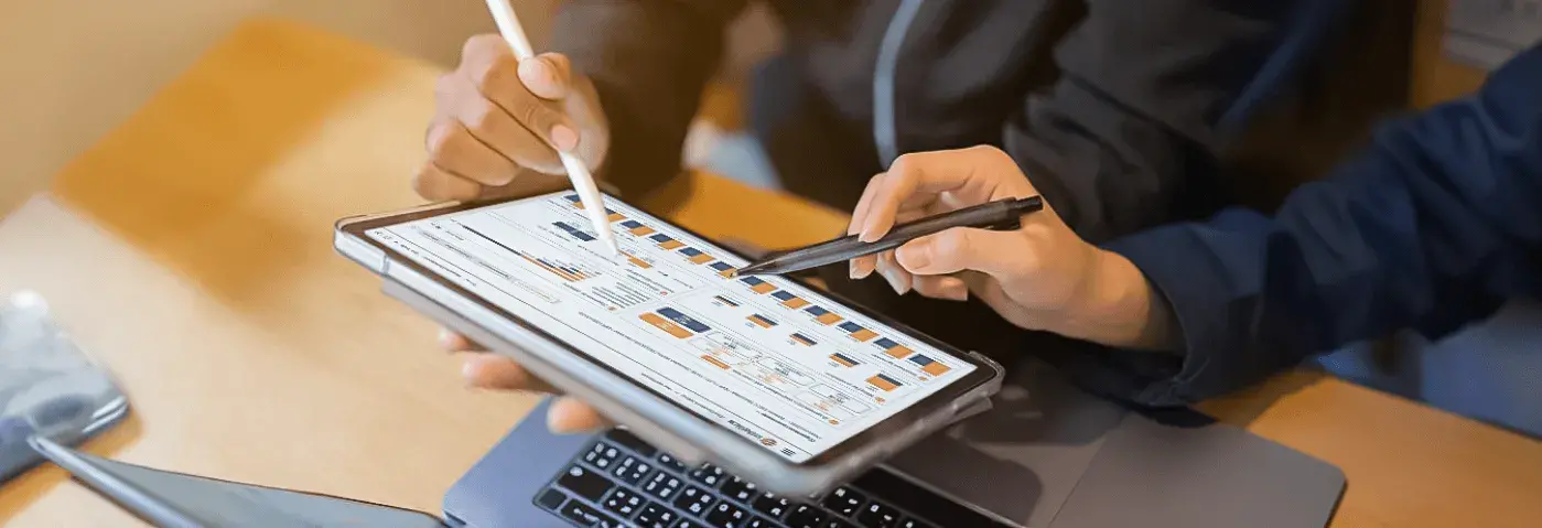 Two people reviewing cost analysis on a tablet with charts, representinghidden fees in card payment processing.