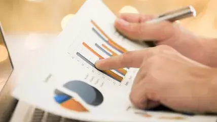 Two people reviewing cost analysis on a tablet with charts, representinghidden fees in card payment processing.